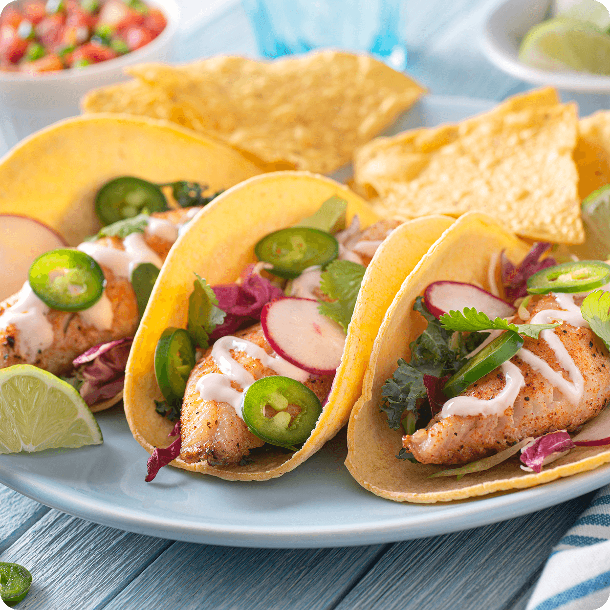 Fish tacos with toppings and tortilla chips.